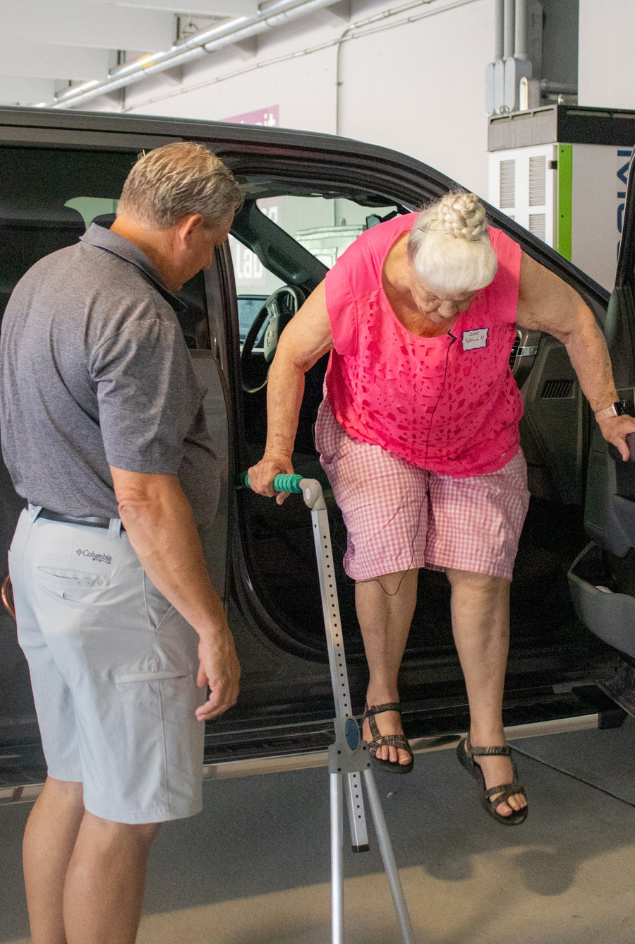 Caregiver assisting a passenger beside a vehicle